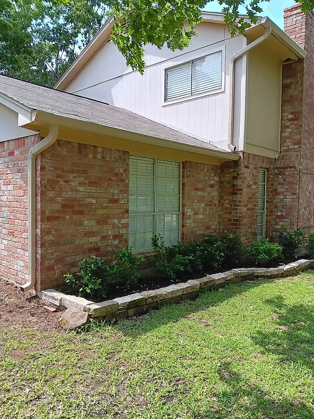 Brick and siding home with gutter routing near the lawn