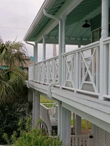 White downspout routing beside a raised coastal-style home