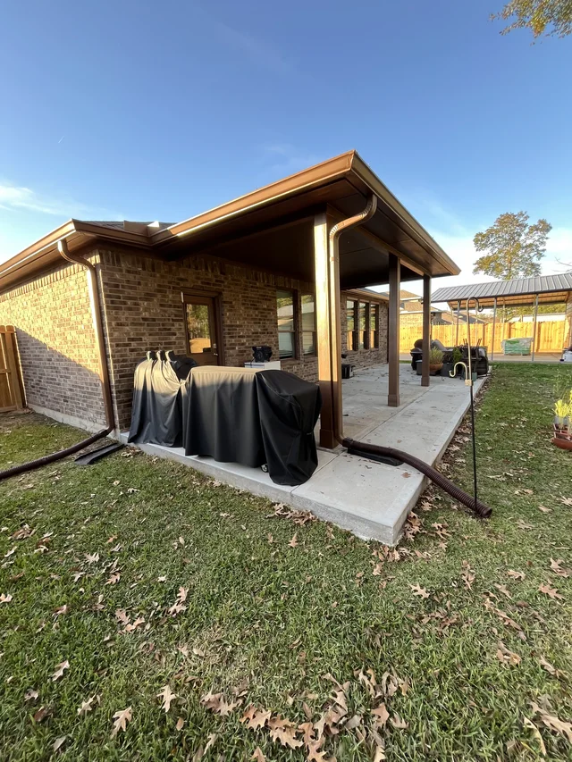 Gutter and downspout routing around a covered outdoor living area