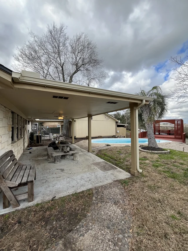 Gutter and downspout routing around a covered outdoor living area