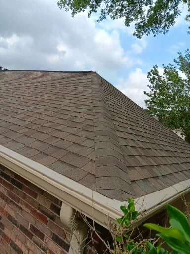 View along the open gutter channel at a shingle roof edge