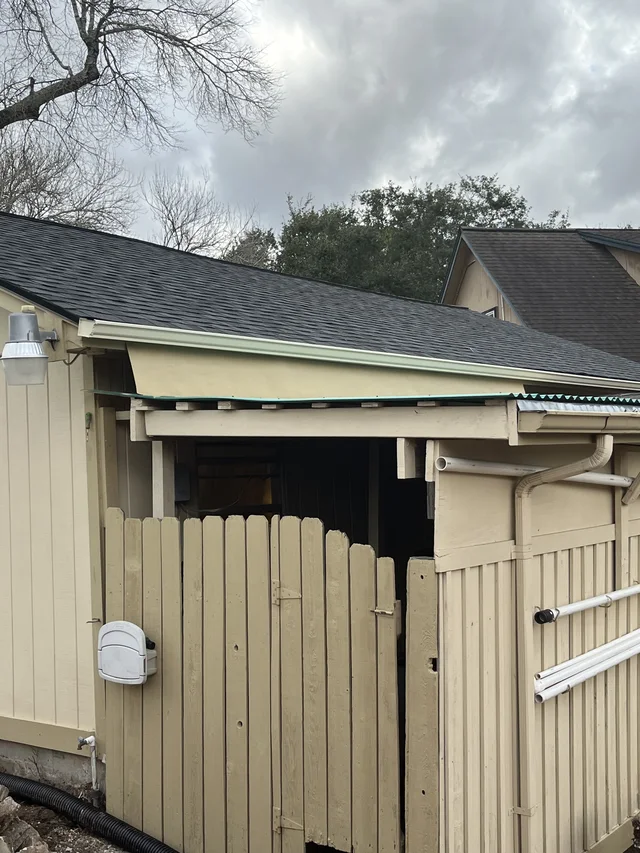 Gutters tracing the roof edge beside an enclosed yard
