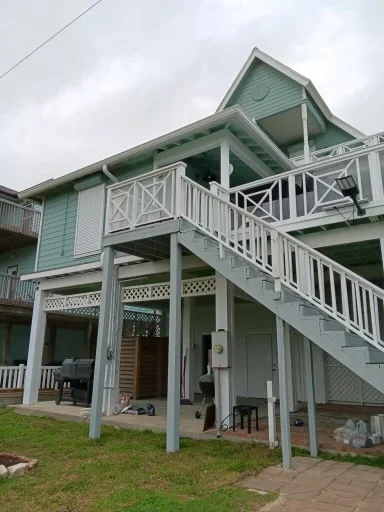 White downspout routing beside a raised coastal-style home