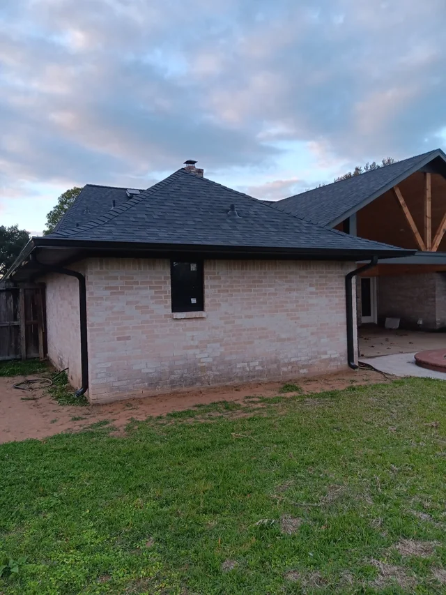 Dark gutters and downspouts around a brick exterior