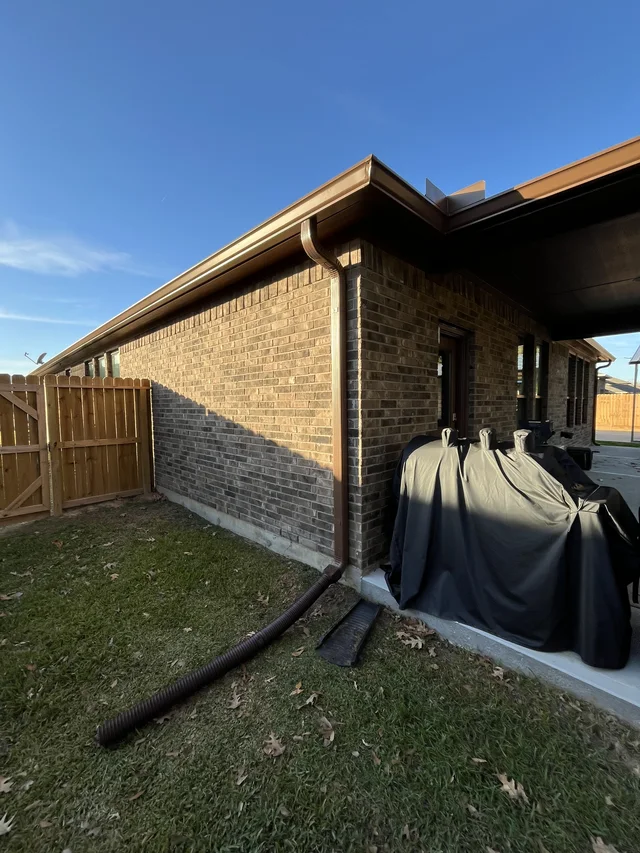 Gutter and downspout routing around a covered outdoor living area