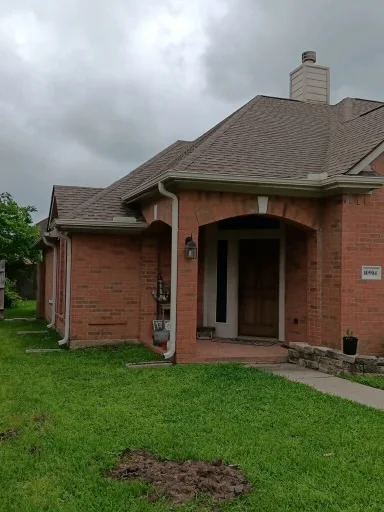Pale gutter and downspout at the corner of a brick home