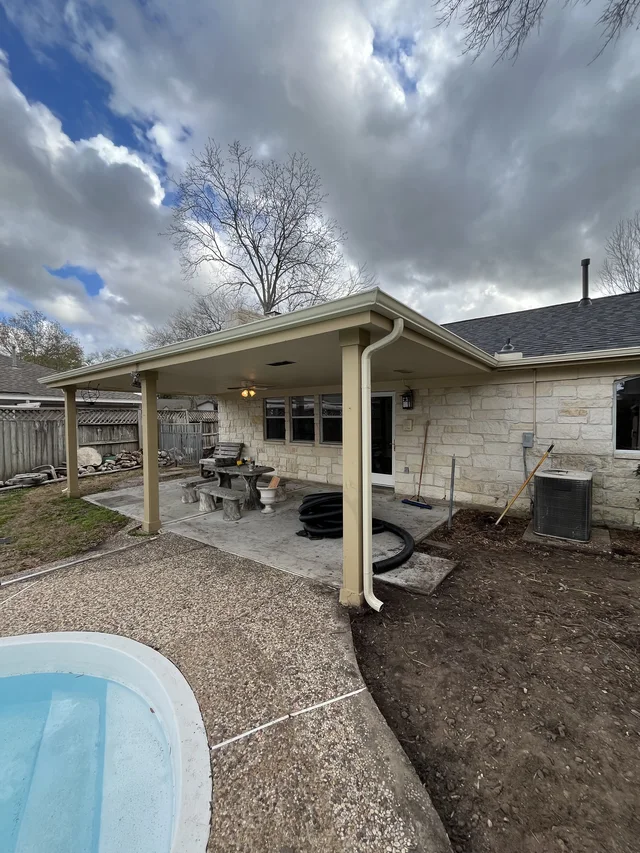 Gutter and downspout routing around a covered outdoor living area