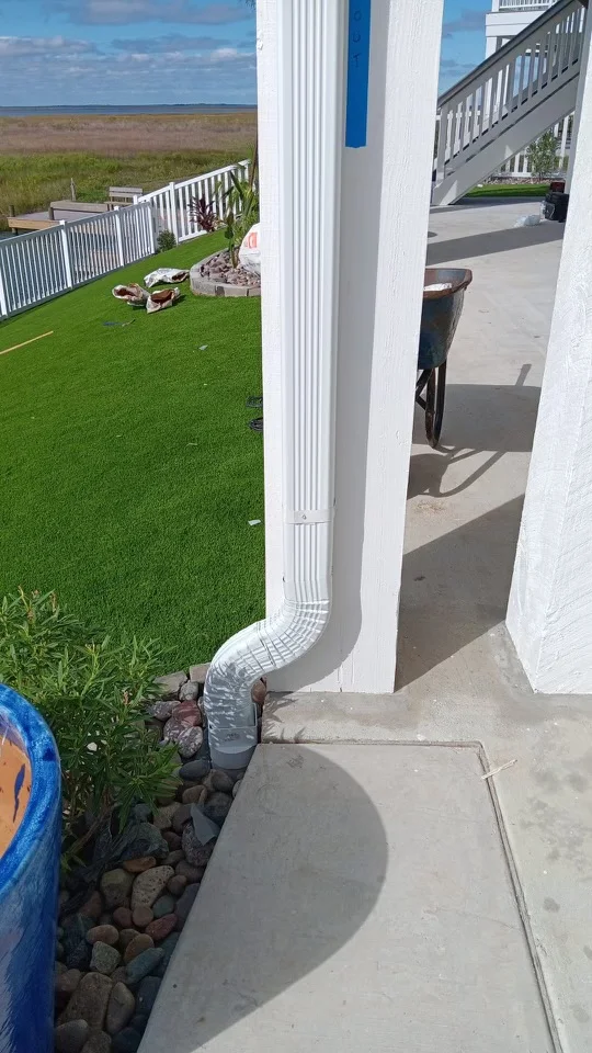 White downspout routing beside a raised coastal-style home