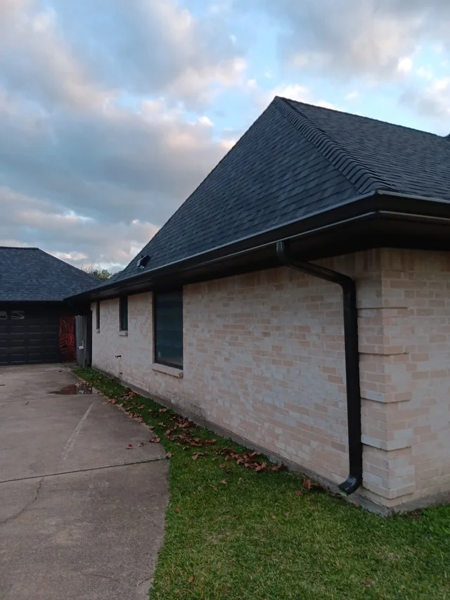 Dark gutters and downspouts around a brick exterior