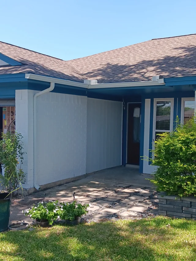 Gutters tracing the roof edge beside an enclosed yard