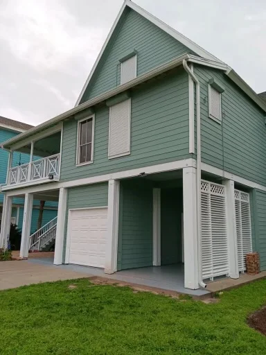 White downspout routing beside a raised coastal-style home
