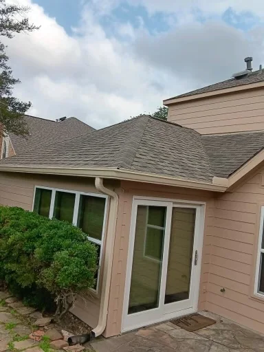 Pale gutter and downspout at the corner of a brick home