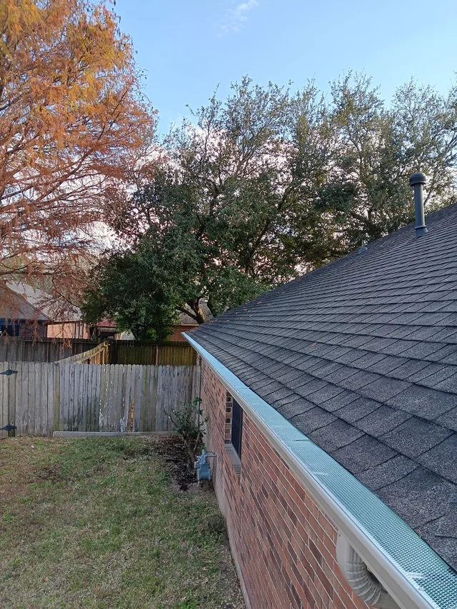 View along the open gutter channel at a shingle roof edge