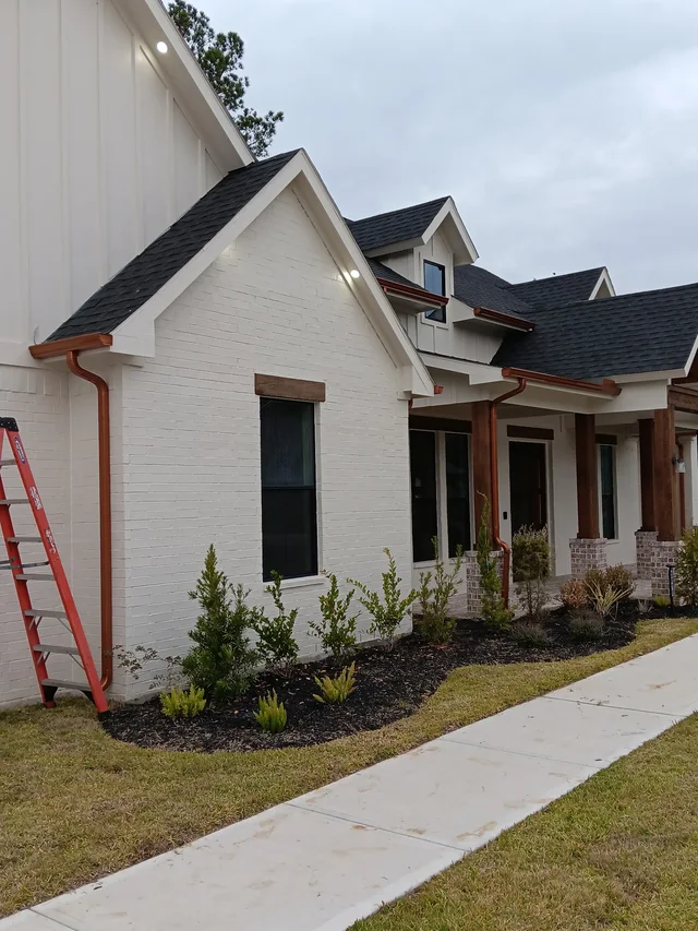 Warm-tone downspouts against a light stucco exterior