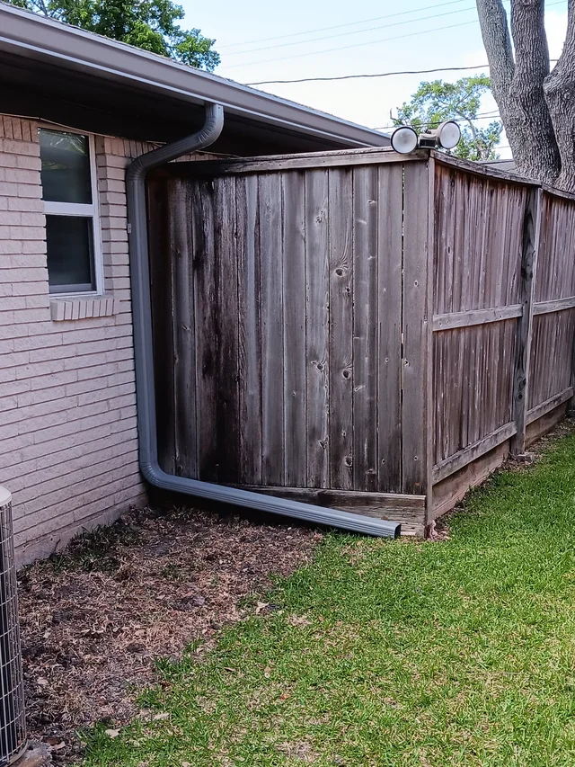 Gutters tracing the roof edge beside an enclosed yard
