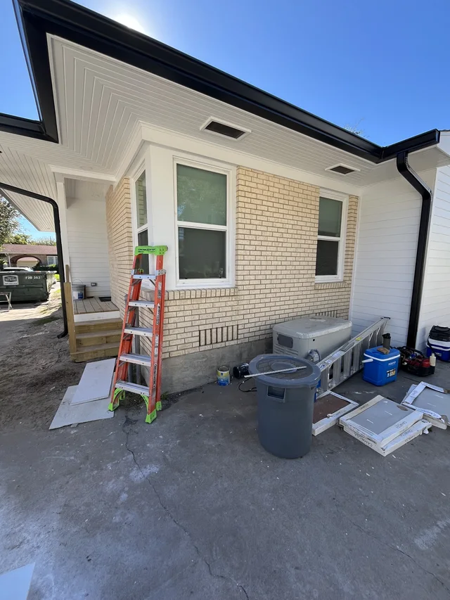 Black gutters along a light exterior with installation ladders