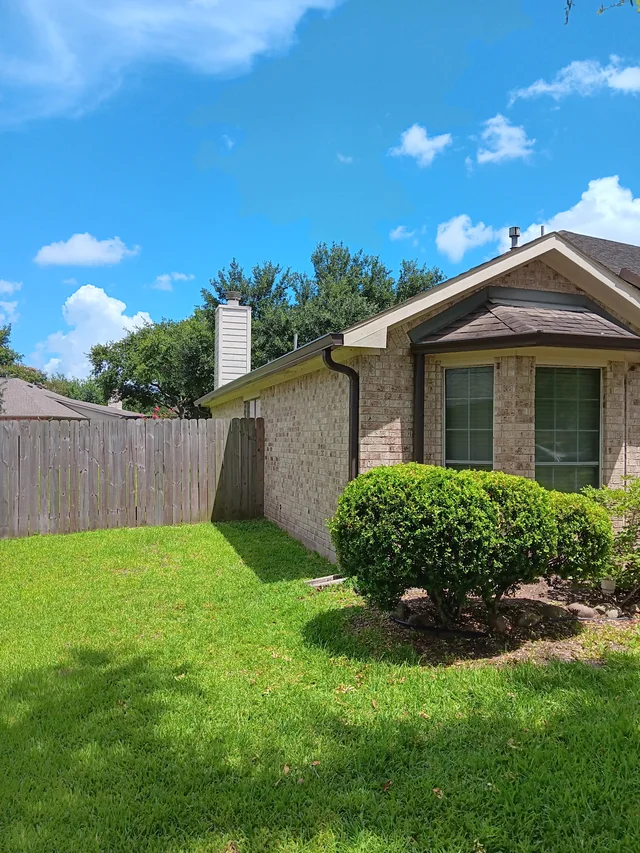Dark gutters and downspouts around a brick exterior
