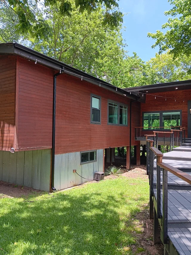 Dark gutter routing along a wood-sided home