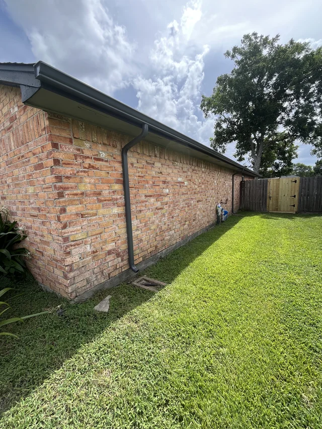 Gutters tracing the roof edge beside an enclosed yard