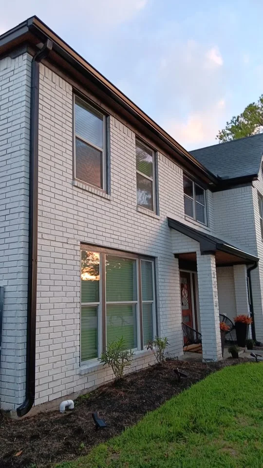 Black downspout contrasting with light siding and brick