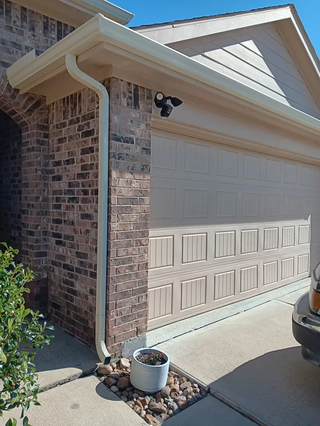 Downspout following the corner of a light brick wall