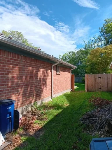 Pale gutter and downspout at the corner of a brick home