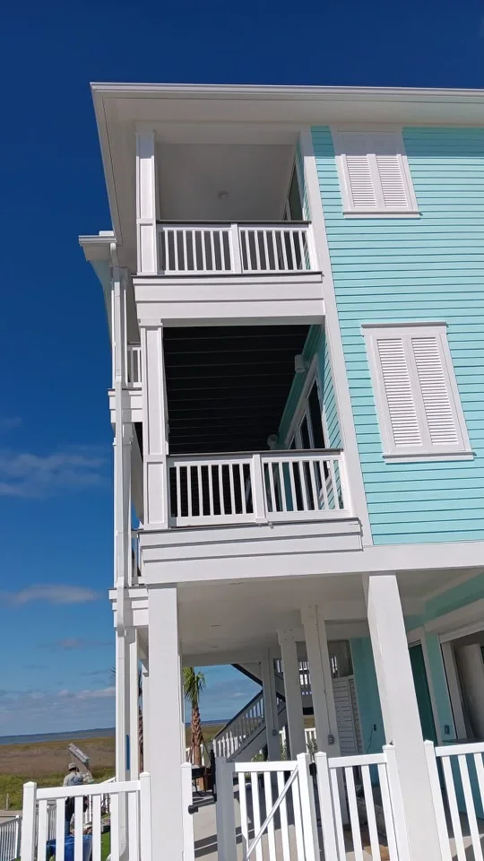 White downspout routing beside a raised coastal-style home