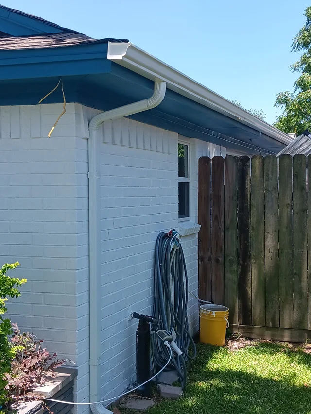 Gutters tracing the roof edge beside an enclosed yard