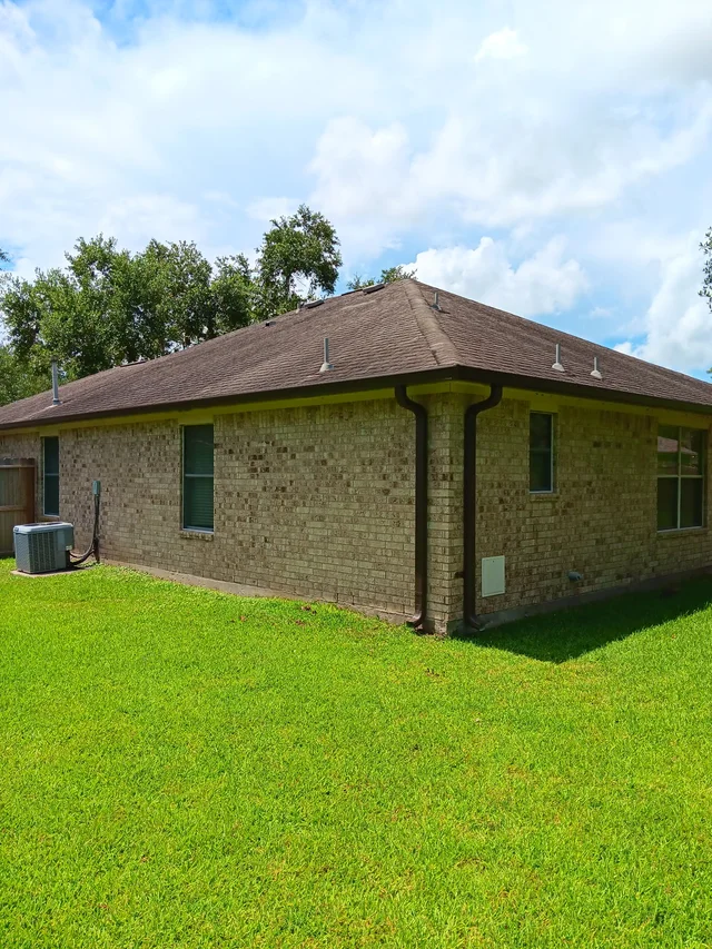Dark gutters and downspouts around a brick exterior