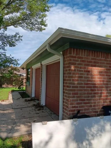 Pale gutter and downspout at the corner of a brick home