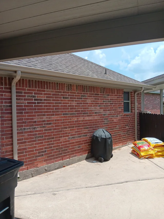 Gutters tracing the roof edge beside an enclosed yard