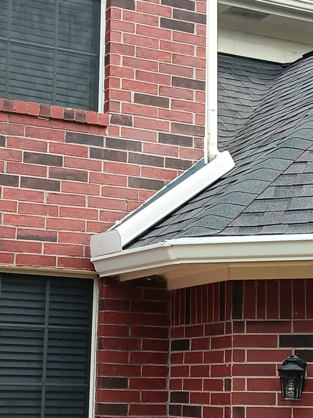 Close view of a white gutter where two roof levels meet