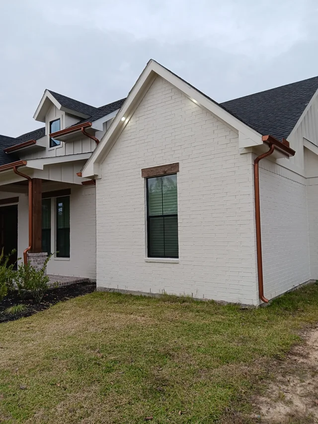 Warm-tone downspouts against a light stucco exterior