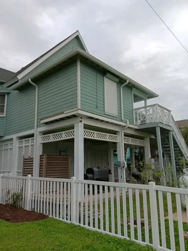White downspout routing beside a raised coastal-style home