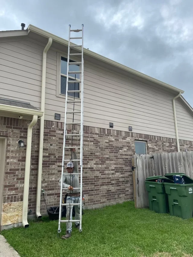 Installation ladder positioned beneath a second-story gutter