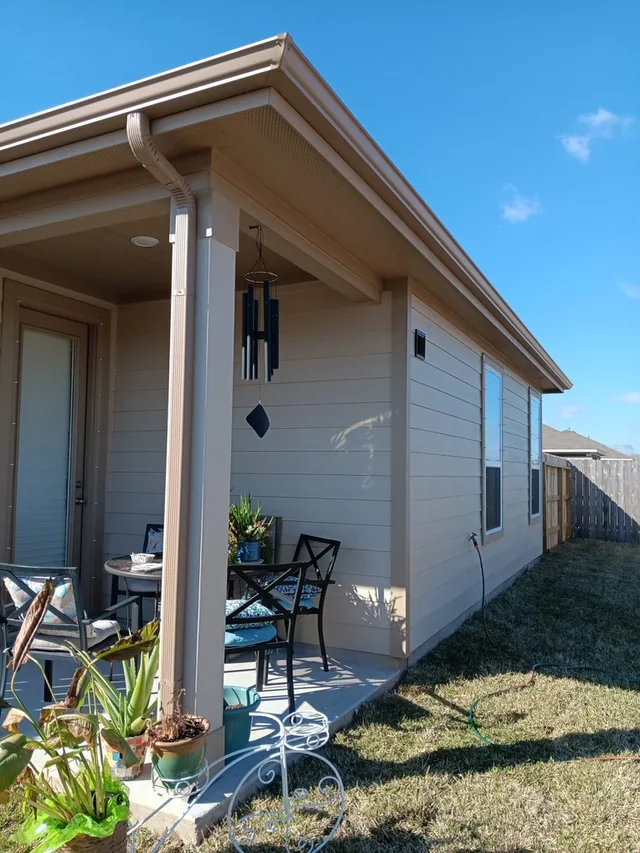 Gutter and downspout routing around a covered outdoor living area