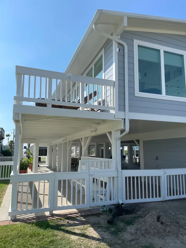 White downspout routing beside a raised coastal-style home