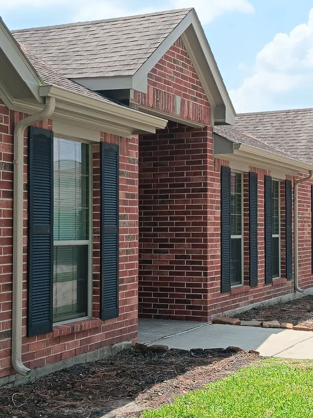 Dark gutters and downspouts around a brick exterior