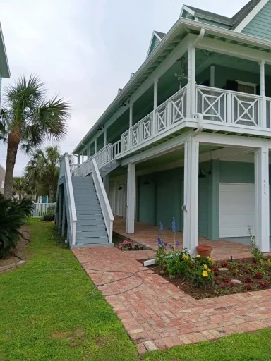 White downspout routing beside a raised coastal-style home