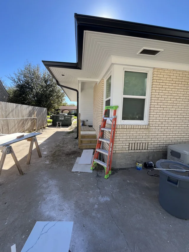Black gutters along a light exterior with installation ladders