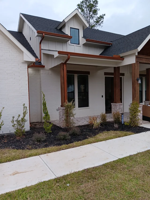 Warm-tone downspouts against a light stucco exterior