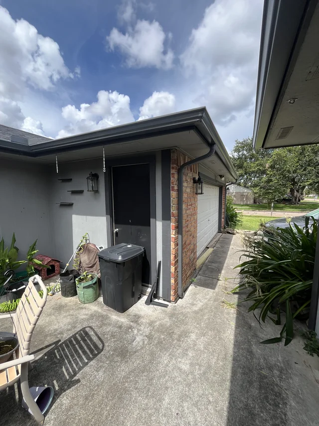 Gutter and downspout routing around a covered outdoor living area