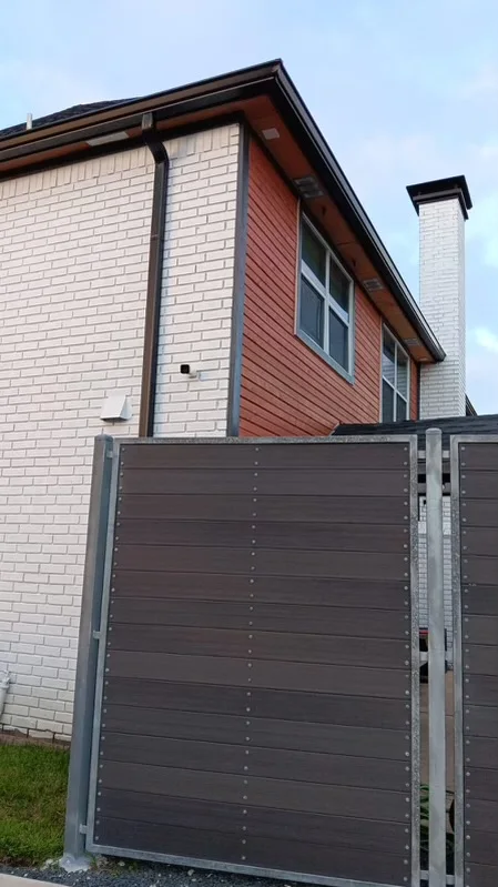 Black downspout contrasting with light siding and brick
