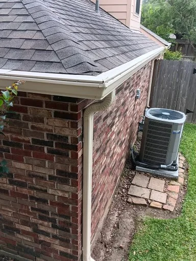 View along the open gutter channel at a shingle roof edge