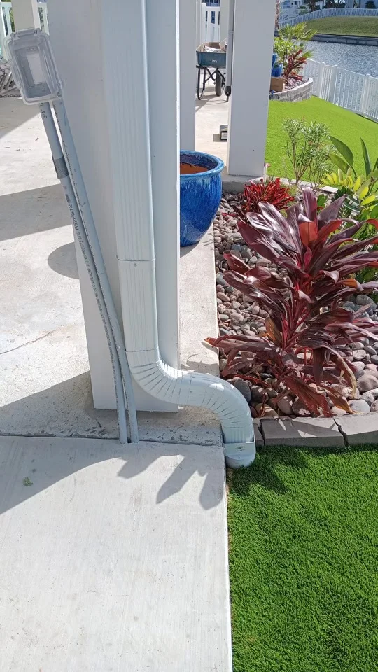 White downspout routing beside a raised coastal-style home
