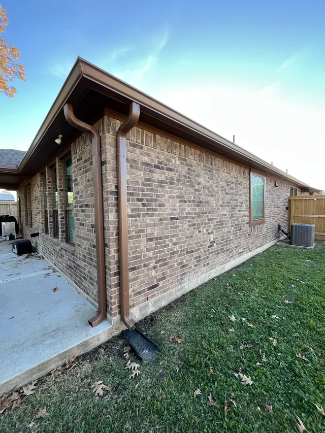 Dark gutters and downspouts around a brick exterior