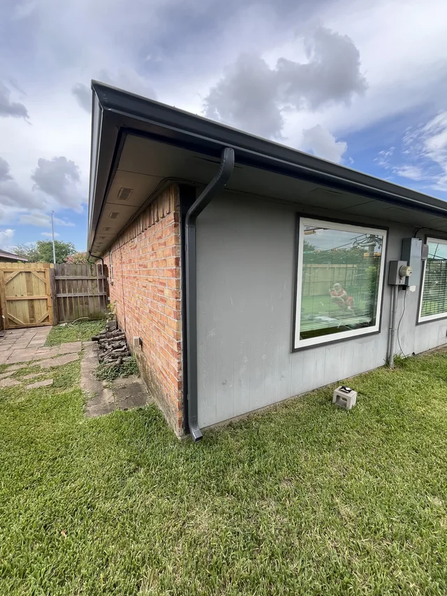 Gutters tracing the roof edge beside an enclosed yard