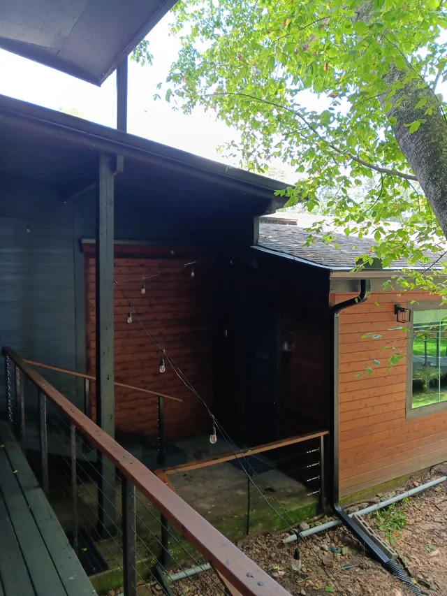 Dark gutter routing along a wood-sided home